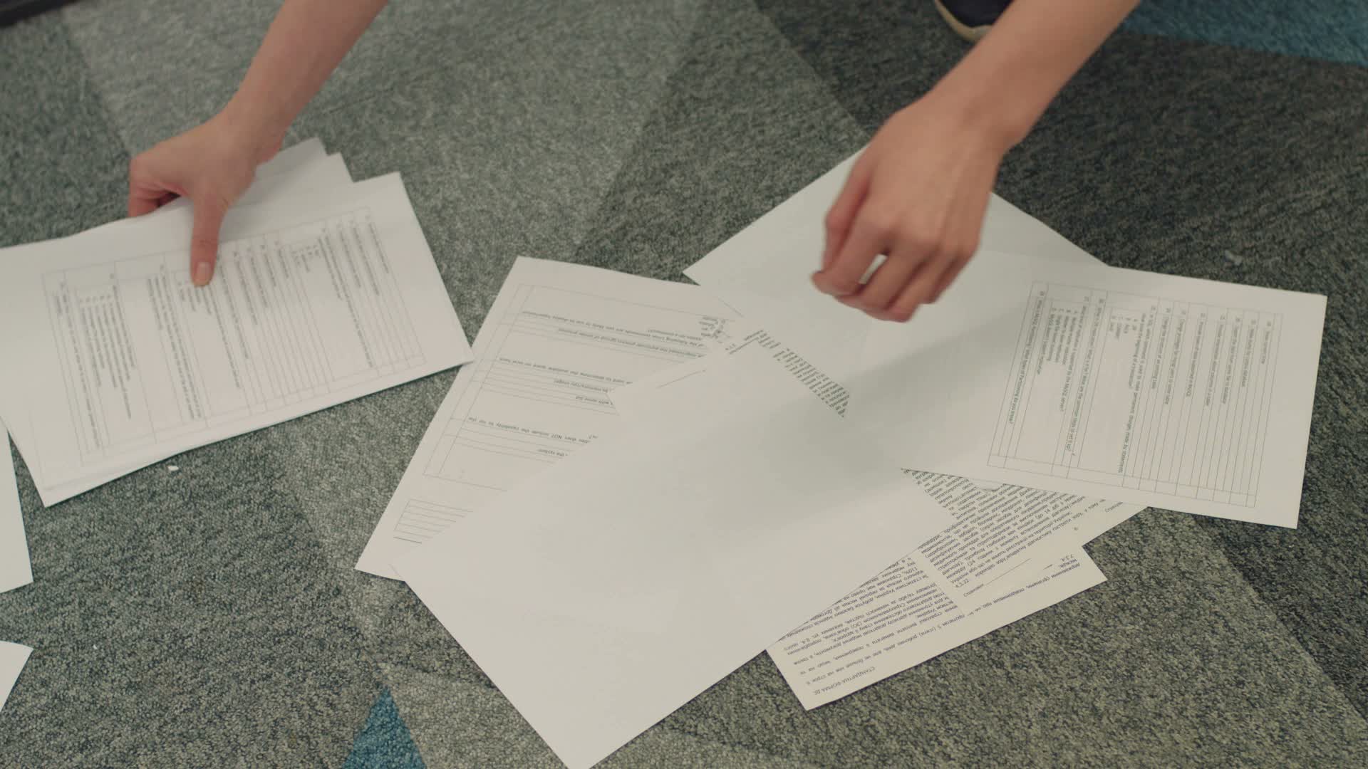Manos organizando formularios y documentos de evaluación Manos organizando formularios y documentos de evaluación sobre una mesa de oficina.